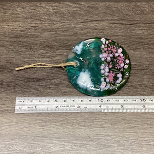 Fused Glass hanging disc with sea pinks scene, with a ruler to demonstrate the entire length of the product, including the twine hanger.