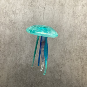 fused glass light aqua jellyfish on a gray surface