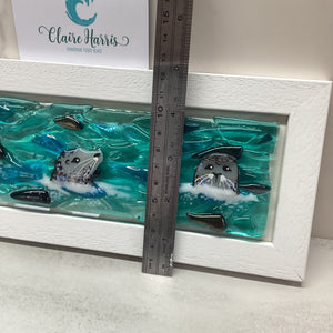 Framed artwork with a ruler for scale and demonstrating the height of the piece, featuring a design of the Trio of Seals. 