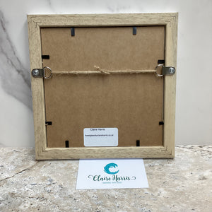Fused Glass Square Framed Agapanthus. Back of a wooden picture frame with Claire Harris branding on a marble surface. 