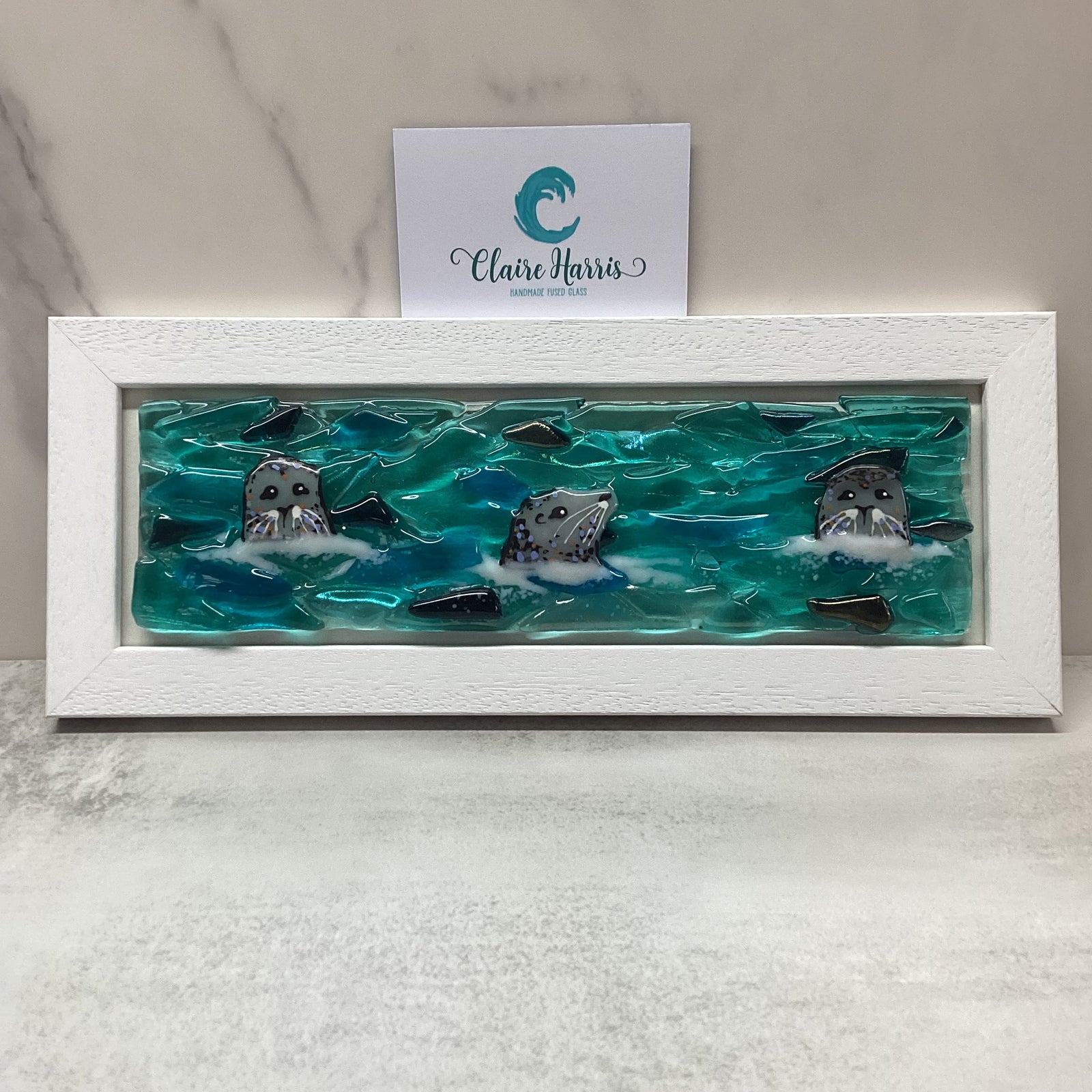 Regular sized framed Trio of Seals main product photo, with a business card.